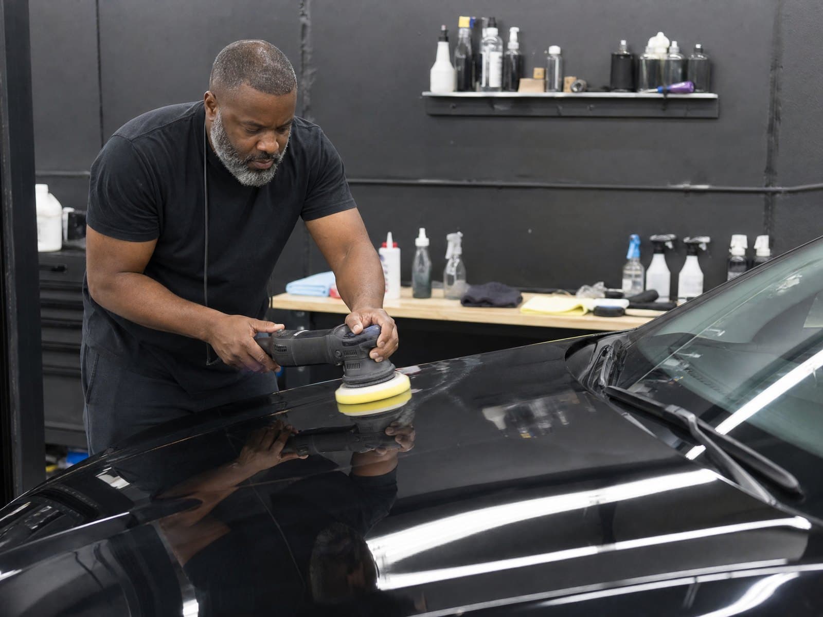 Machine polishing a black car's hood